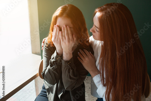 Cuadro en lienzo Young woman crying in a cafe covers her face with hands