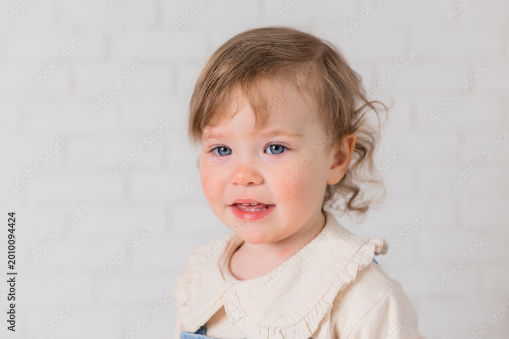 Naklejka premium portrait of a little girl with blond curly hair and blue eyes