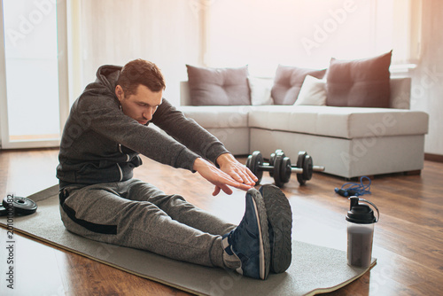 Obraz na plátne Young ordinary man go in for sport at home