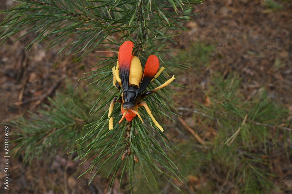 Obraz premium Toy hornet replica resting on green pine tree needles simulating a wildlife scene in nature