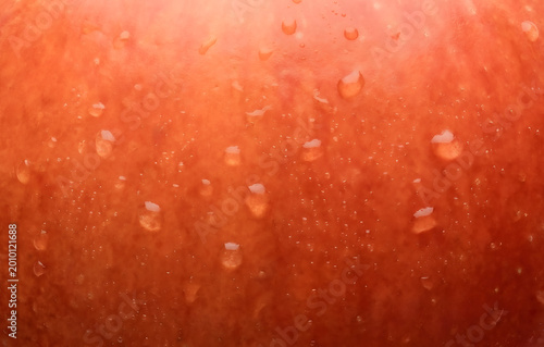 Macro texture of fresh red apple skin with clear water drops, organic fruit surface background for healthy food concept.