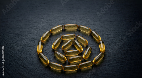Close-up of Gelatin Capsules Arranged in a Circular Pattern on a Dark Surface for Supplement Illustration