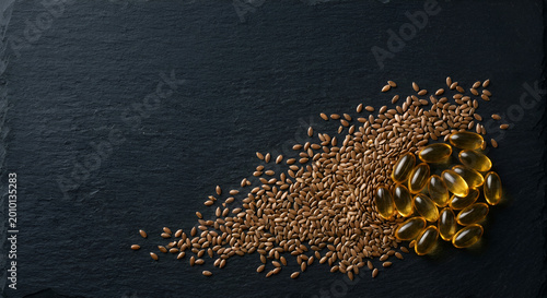 Glossy golden capsules and scattered hemp seeds arranged artistically on a dark textured surface