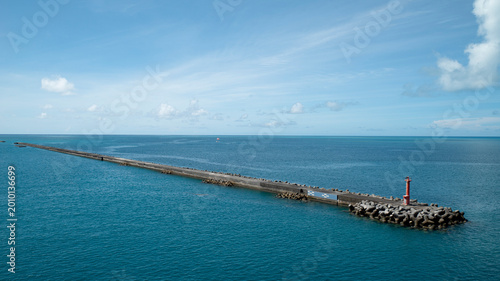 Foto Modern aesthetic wide shot of a red lighthouse on a long breakwater into a calm