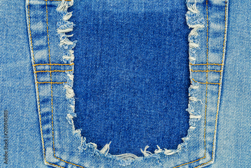 Bild auf Leinwand Torn denim fabric with frayed edges and a cutout section in blue color