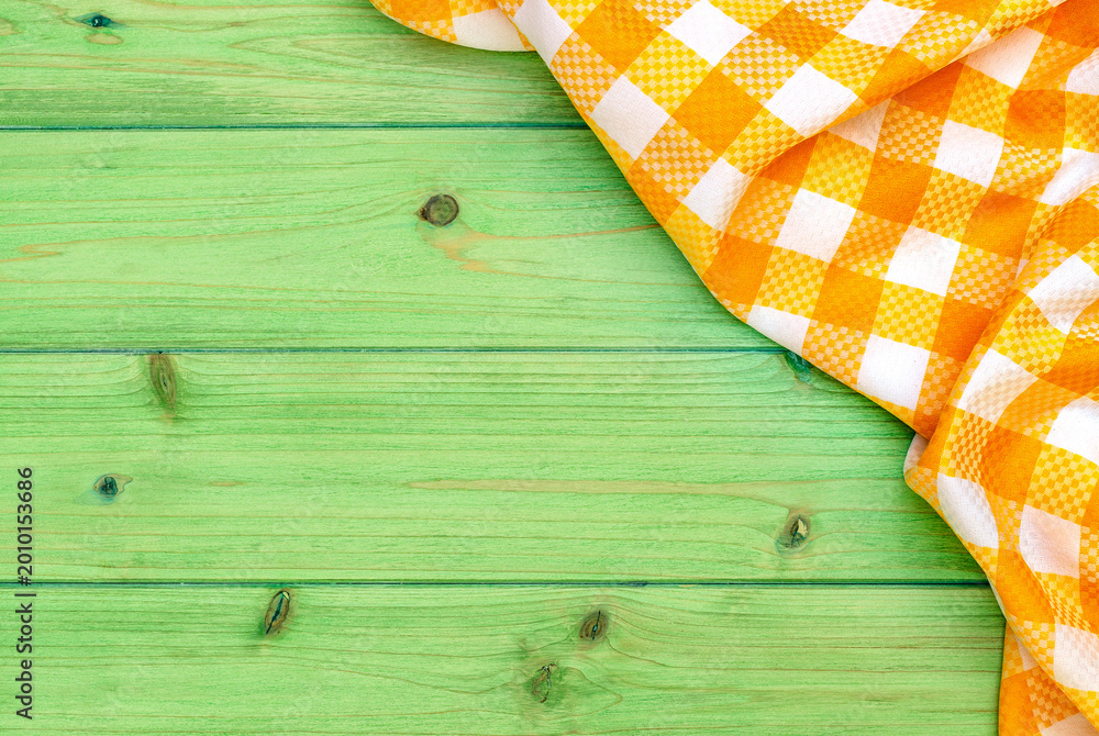 Fototapeta premium Checkered cloth on a green wooden table ready for a meal outside during a warm day in a garden setting