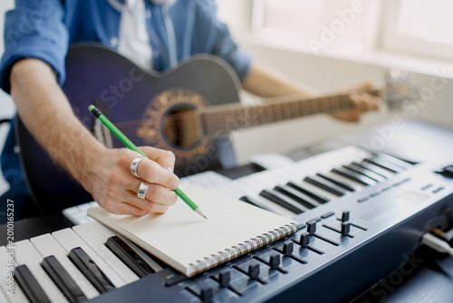 Photos Male music arranger composing song on midi piano and audio equipment in digital recording studio