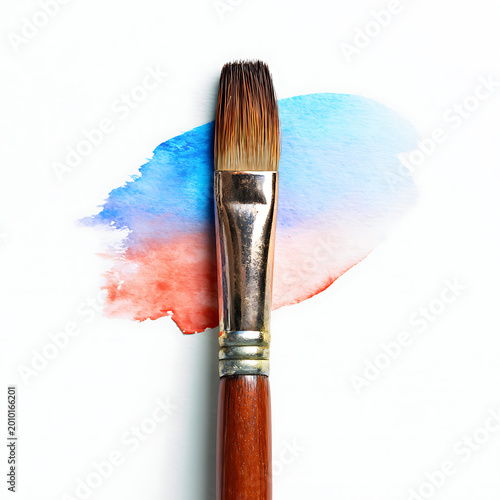 Paintbrush resting on watercolor stain with blue and red colors  