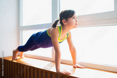 Obraz na plátne Little girl Doing a Plank Exercise workout at home