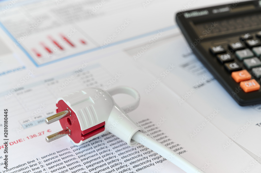 Fototapeta premium A red and white electric plug is on top of service documents with a calculator nearby in an office space