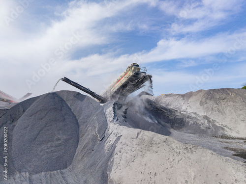 Granite quarry site with machinery processing stone at work during the day under a blue sky and some clouds