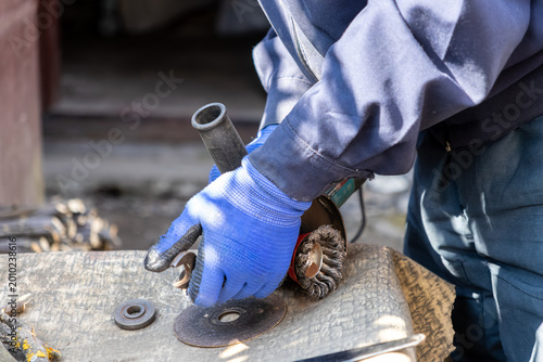 Εκτύπωση καμβά Worker wearing protective blue gloves using an angle grinder with wire wheel bru