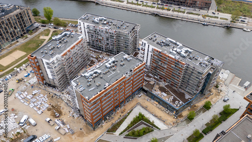 Aerial view of a modern residential complex under construction near the river, urban development and real estate investment in Gdansk, Poland.