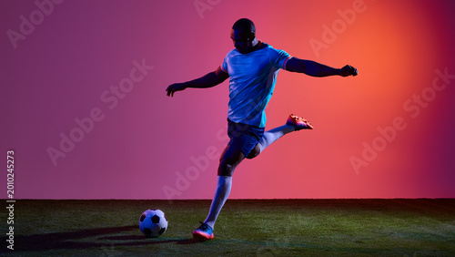 Photos Football player preparing penalty kick on grass field with neon gradient background