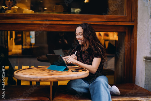 Canvastavla She scrolls or taps on tablet screen with stylus in motion, smiling softly — a moment of digital browsing or design work, showing ease and fluency with tech in modern freelance life