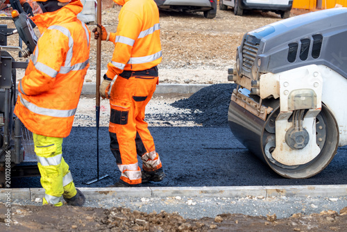 Fotografía Workers lay asphalt on a construction site while using machinery and equipment i