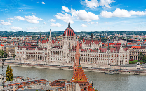 The Hungarian Parliament Building stands majestically along the banks of the Danube River under a bright blue sky in Budapest.