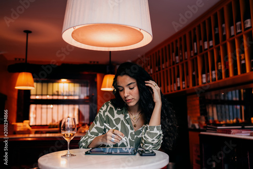 Fotografía Portrait mode of woman smiling while interacting with smartphone at her tablet station, expressing satisfaction and digital fluency in modern creative environment