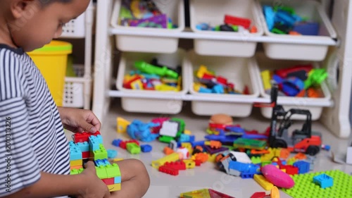 Child playing with colorful plastic building blocks on the floor, hands assembling toy bricks, early learning, creativity, motor skills development, education concept, playful childhood activity.