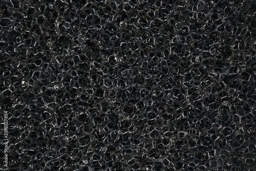 Abstract macro shot of black porous sponge cellular foam texture.