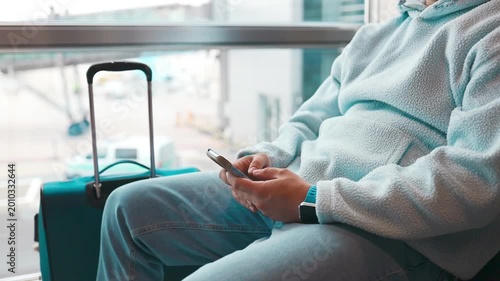 Unrecognizable man in casual outfit holding passport and flight tickets, suitcase on background, male getting ready for departure. Travelling, tourism concept. High quality FullHD footage