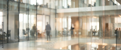 Fotografi An abstract view of a modern office building's interior featuring glass walls and blurred silhouettes of people working in a collaborative environment