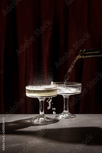 Pouring Champagne into Elegant Glass on Dark Red Background