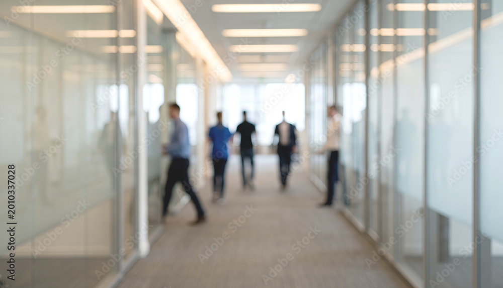 Fototapeta premium Blurred image of a modern office hallway with professionals walking. The glass walls create a contemporary, open workspace environment.