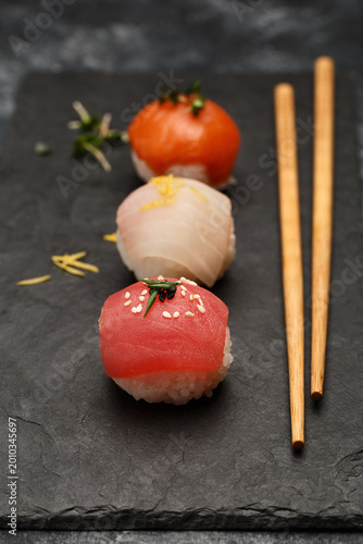 Canvastavla Sushi nigiri set with salmon, tuna and sea bass on black slate plate with chopsticks over dark concrete background
