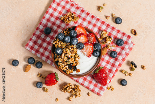 Yogurt bowl with granola and fresh berries for breakfast. Healthy breakfast, wholesome eating, homemade granola recipe concept. A top view flat lay.