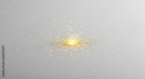 Glowing golden particles spreading out on a gray background creating a bright sparkling effect