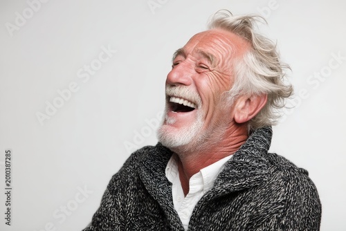 Portrait of a jovial caucasian man in his 60s laughing in front of white background
