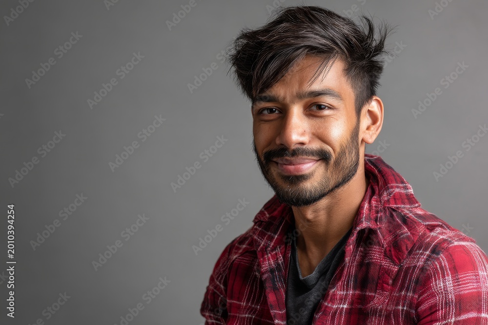 Fototapeta premium Portrait of a happy indian man in his 30s smiling at the camera isolated on soft gray background