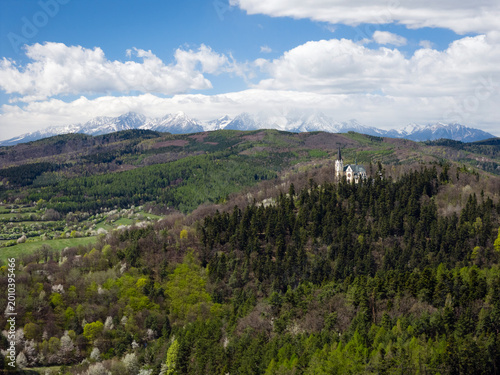 Breathtaking spring view of the Marianska hora pilgrimage site in Levoca, with the snow-capped High Tatras mountains in the background
