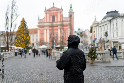 Foto Rear view of man walking across Triple Bridge in Ljubljana Slovenia with Francis