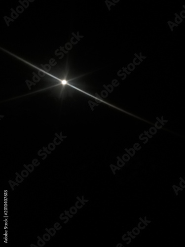 Diagonal anamorphic lens flare with bright light streak on black background