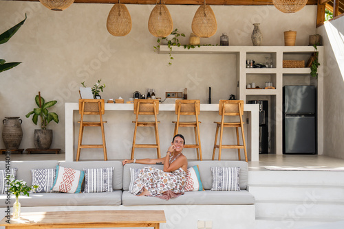 Smiling woman enjoying vacation time on a comfortable couch in a tropical resort lounge