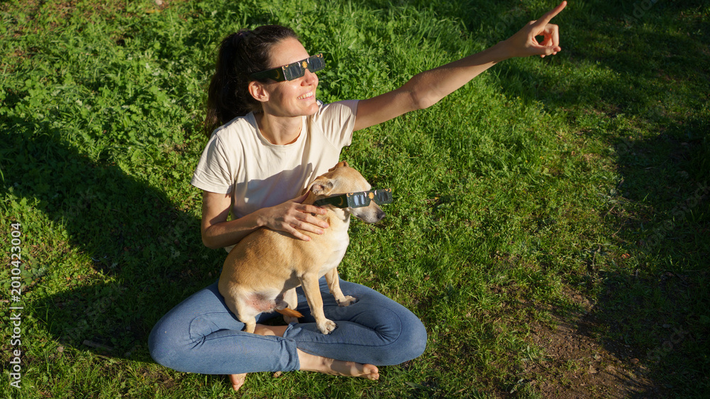 Obraz premium Woman and dog enjoying solar eclipse viewing together