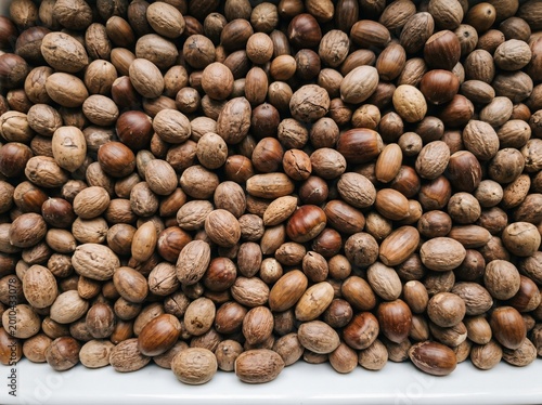 A large pile of brown and tan colored pecans on a white surface