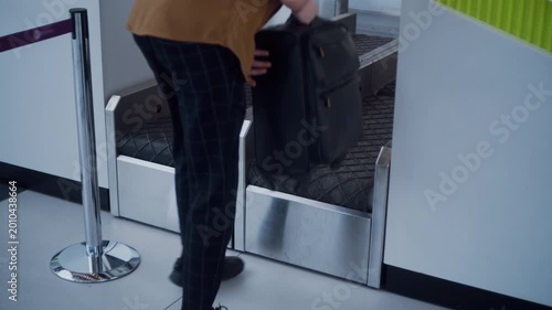 Man placing his rolling baggage on the conveyor belt system at the airport check-in counter