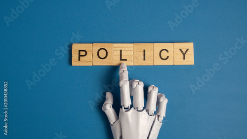 Foto White robotic hand pointing to the word policy on wooden blocks over a blue background representing artificial intelligence ethics and government regulations