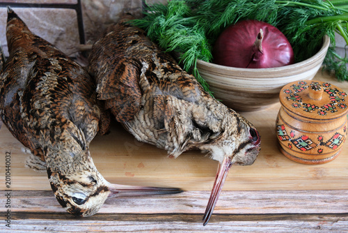 Photos Two woodcocks on a cutting board with onions and herbs