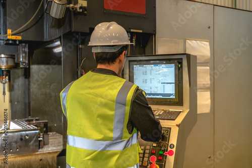 Rear view industrial engineer man working on machine monitor for inspecting manufacturing control system 