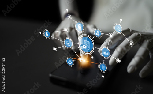 Vászonkép A close-up view of hands interacting with a smartphone, surrounded by floating digital icons that symbolize data connections and modern technology in a contemporary workspace