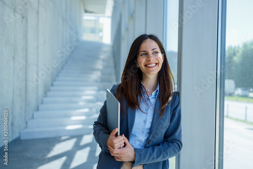 Businesswoman holding tablet smiling standing in modern office