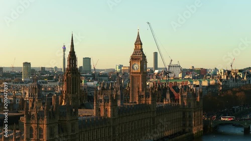 Golden hour illuminating Palace of Westminster and Elizabeth Tower, revealing London's historic architecture and River Thames flowing through the capital city
