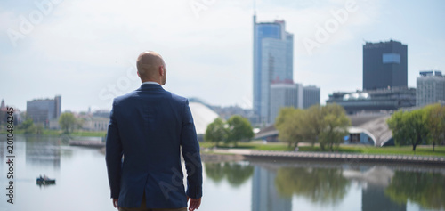 Successful businessman looking at city skyscrapers skyline dreaming of future opportunities with copy space