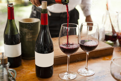 Waiter Pouring Red Wine into Glasses at Elegant Outdoor Event
