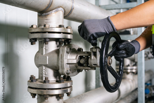 Fotografía Industrial worker in gloves turning a large valve on a complex pipe system