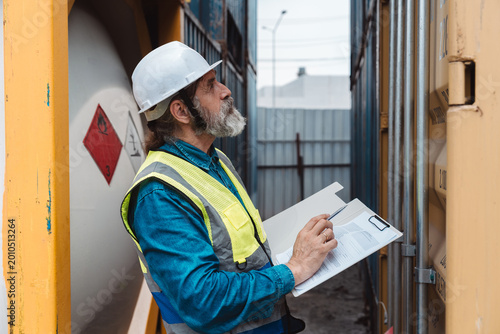 Quadro su tela Senior industrial safety inspector pointing at hazardous caution label on cargo container